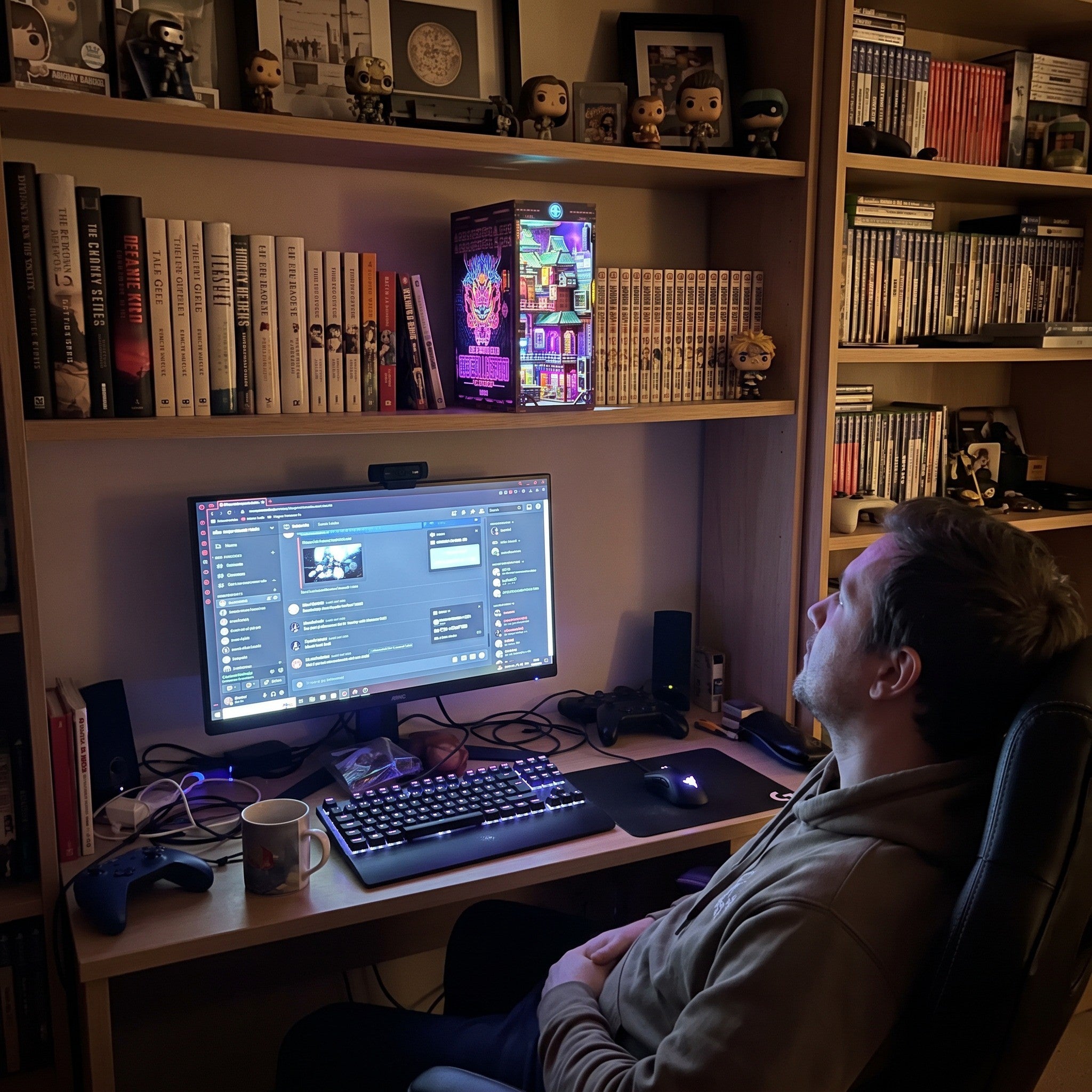 Man viewing a lit book nook above his gaming monitor